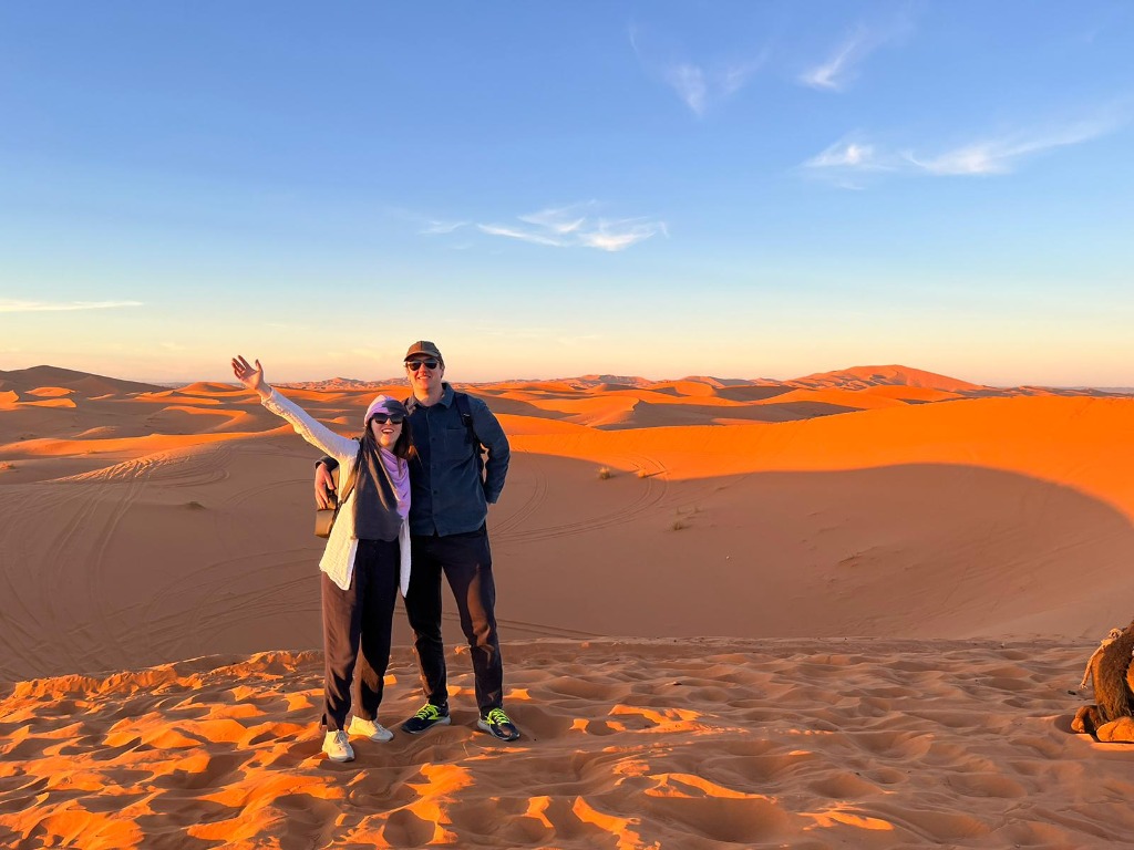 Travelers enjoying Sahara desert dunes